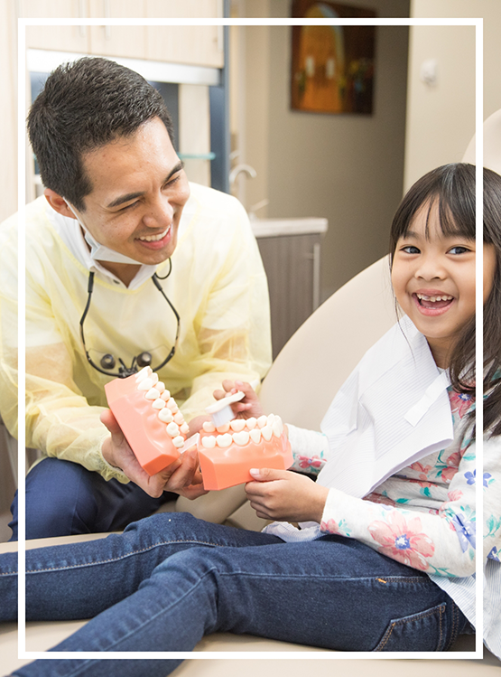 Doctor Kham showing a young girl patient a model of the teeth