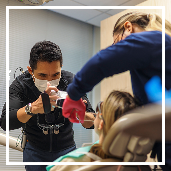 Close up of a person with flawless teeth pointing to their smile