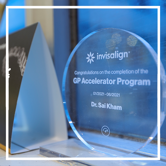 Smiling blonde woman holding an Invisalign clear aligner