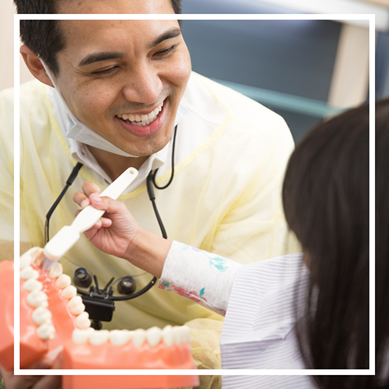 Doctor Kham showing a model of the teeth to a young patient